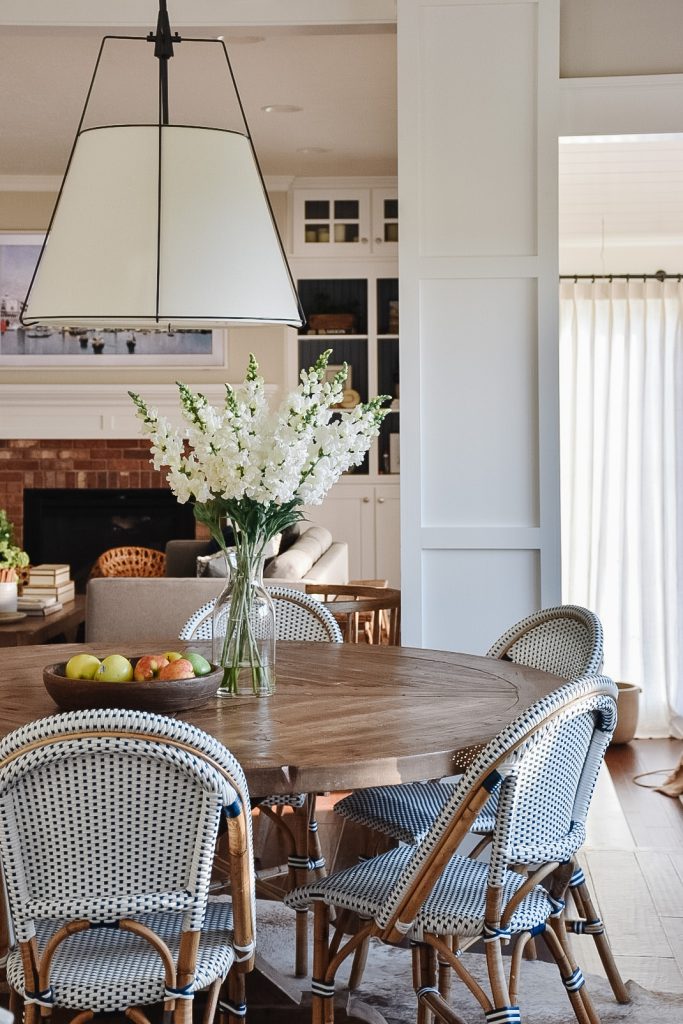 Rustic dining table accompanied by bistro chairs and styled with white flowers.